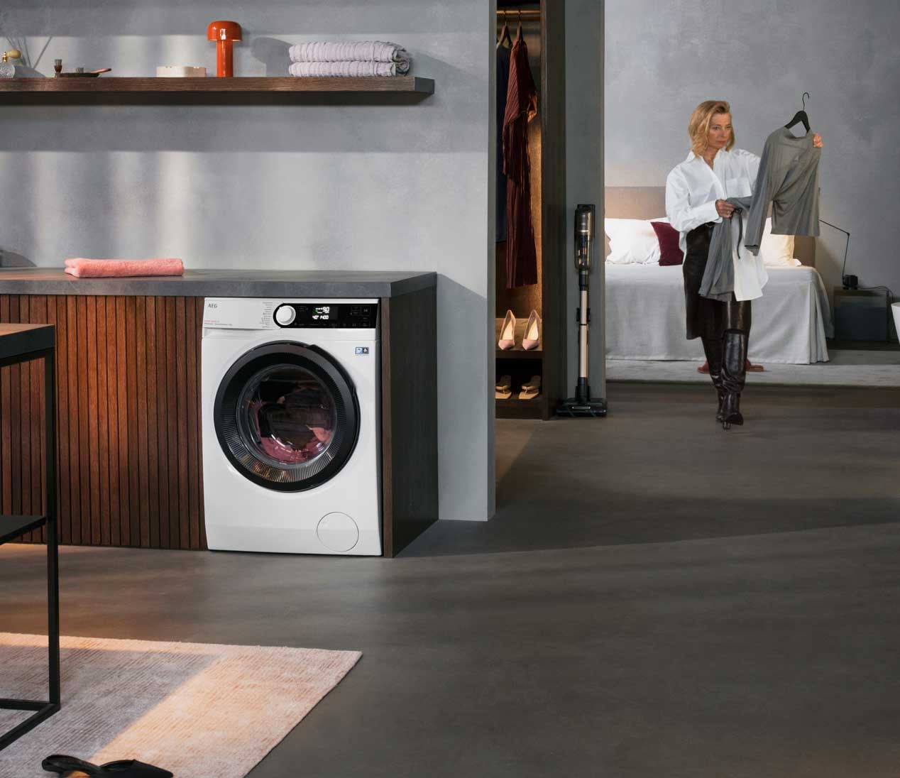 Kvinne går mot vaskemaskinen med klær i armene